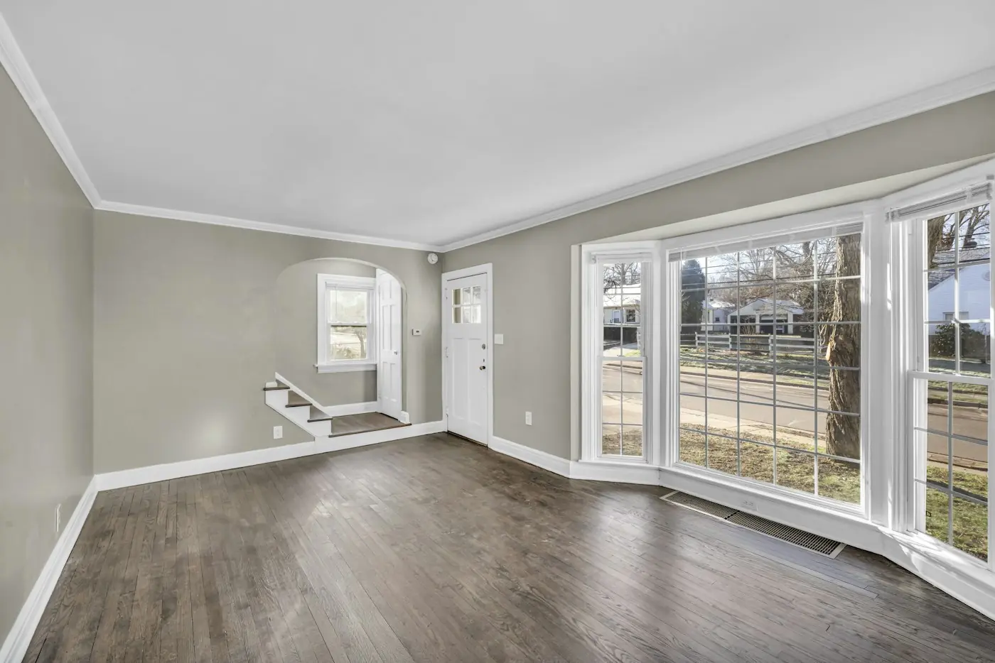 An empty, freshly prepared rental room with wood floors and bright windows